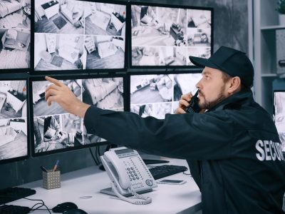 Male security guard using radio transmitter in surveillance room