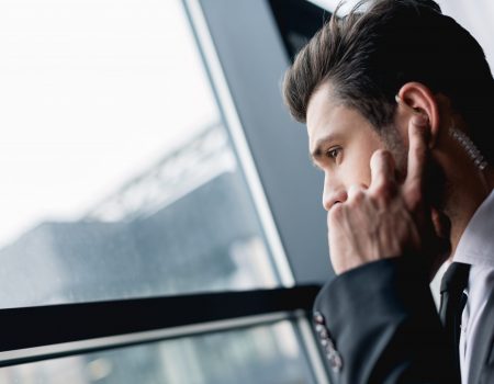 handsome bodyguard in black suit using earphone
